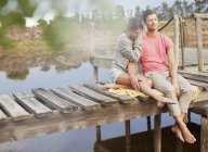 Серена пара сидить на причалі над озером — стокове фото