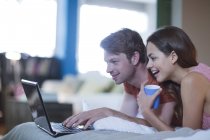 Couple using laptop together on bed — Stock Photo