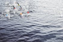 Уверенные и сильные триатлонисты, брызгающиеся в воде — стоковое фото
