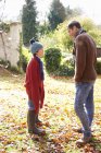 Father and son walking in autumn leaves — Stock Photo