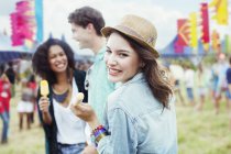 Portrait of woman eating flavored ice with friends at music festival — Stock Photo