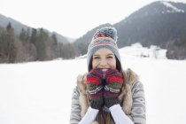 Retrato de mulher entusiasta usando chapéu de malha e luvas no campo nevado — Fotografia de Stock