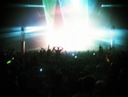 Fans facing illuminated stage — Stock Photo