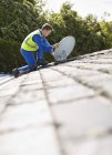 Вмілий білий працівник встановлює супутникову тарілку на даху — стокове фото