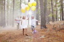 Familia feliz con globos en el bosque - foto de stock