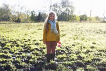 Smiling girl standing in muddy field and looking aside — Stock Photo