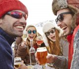 Friends celebrating with drinks in snow — Stock Photo