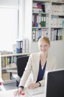 Портрет усміхненої бізнес-леді за столом в офісі — стокове фото