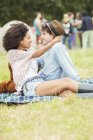 Пара обіймає ковдру в траві на музичному фестивалі — стокове фото