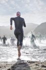 Вид сзади триатлонистов на старте плавательной гонки — стоковое фото