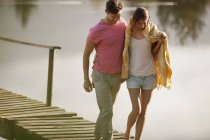 Happy couple walking on dock over lake — Stock Photo