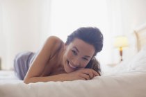 Ritratto di donna sorridente sdraiata a letto — Foto stock