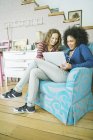 Women using laptop together in armchair — Stock Photo