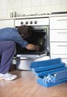 Geschickter kaukasischer Elektriker arbeitet am Ofen in der Küche — Stockfoto