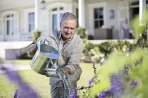 Uomo anziano caucasico irrigazione piante in giardino — Foto stock