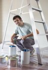 Uomo esame lattine di vernice in camera — Foto stock