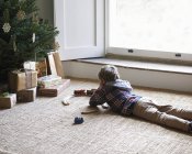 Garçon jouer avec les trains par arbre de Noël — Photo de stock