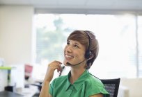 Mujer de negocios hablando en auriculares en el escritorio en la oficina moderna - foto de stock