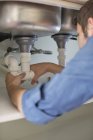Klempner arbeitet an Rohren unter Waschbecken — Stockfoto