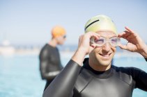 Confident and strong triathletes adjusting goggles outdoors — Stock Photo