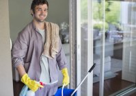Skillful caucasian man carrying bucket of cleaning supplies — Stock Photo