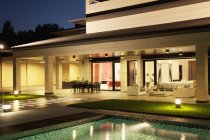Maison de luxe et piscine éclairée la nuit — Photo de stock