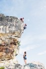 Vista lejana de escaladores escalando empinada roca cara - foto de stock