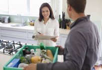 Skillful caucasian woman signing for delivery in kitchen — Stock Photo