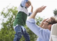 Padre e hijo chocando los cinco al aire libre - foto de stock