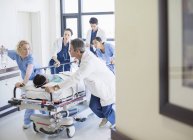Médicos e enfermeiros apressando o paciente na maca no corredor do hospital — Fotografia de Stock