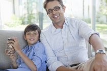 Father and son with change jar on sofa — Stock Photo