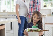 Menina segurando tigela de salada na cozinha — Fotografia de Stock