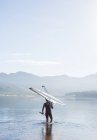 Man carrying rowing scull into lake — Stock Photo