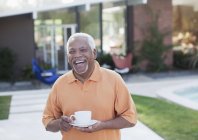 Мужчина постарше пьет кофе на заднем дворе — стоковое фото