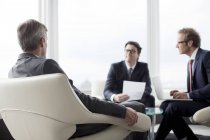 Бизнесмены разговаривают в лобби в современном офисе — стоковое фото