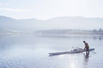 Man placing rowing scull in lake — Stock Photo