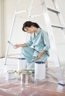 Abile donna caucasica esaminando lattine di vernice — Foto stock