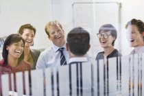 Деловые люди смеются на встрече в современном офисе — стоковое фото