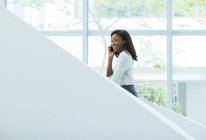 Бізнес-леді розмовляє на мобільному телефоні на офісних сходах — стокове фото