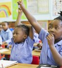 African american students raising hands in class — Stock Photo