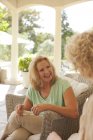 Smiling mother and daughter talking on porch — Stock Photo