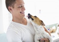 Caucasian smiling man holding cute dog — Stock Photo