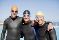 Triatletas confiantes e fortes em fatos de mergulho sorrindo juntos — Fotografia de Stock