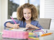 Portrait of curly girl coloring at table — Stock Photo