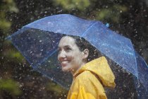 Happy caucasian woman with umbrella in rain — Stock Photo