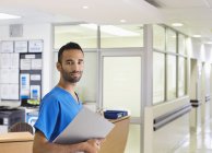 Enfermera masculina sonriendo en el pasillo del hospital - foto de stock