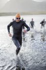 Confident and strong triathletes emerging from water — Stock Photo