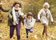Три поколения женщин играют в осенние листья — стоковое фото