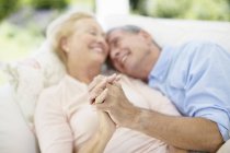 Seniorenpaar hält sich auf Sofa an der Hand — Stockfoto