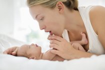 Madre culla neonato sul letto — Foto stock